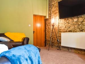 a living room with a television on a stone wall at The Old Boot Room in Llanfynydd