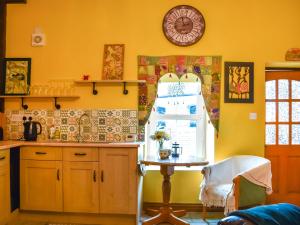 a kitchen with a table and a clock on the wall at The Old Boot Room in Llanfynydd