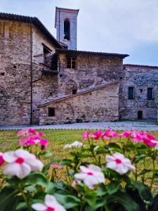 een oud gebouw met roze bloemen ervoor bij O rosa bella in Gubbio