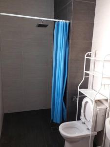 een badkamer met een blauw douchegordijn en een toilet bij Twin Eleven in Kota Bharu