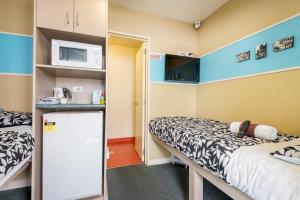 a small room with two beds and a microwave at Stay Hostel Rotorua in Rotorua
