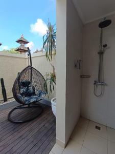 a swinging chair on a deck with a shower at Kala Surf Camp in Uluwatu