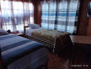 1 Schlafzimmer mit 2 Betten und Fenstern mit Vorhängen in der Unterkunft Hospedaje Aurora in Oxapampa