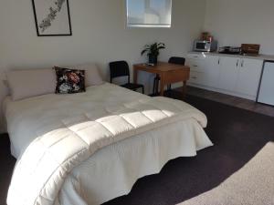 a bedroom with a white bed and a table with chairs at Studios On Carroll - ex Ferry Hotel in Wairoa