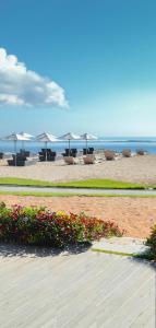 a beach with chairs and tables and umbrellas at IKOSHAROLD Resort Benoa in Nusa Dua