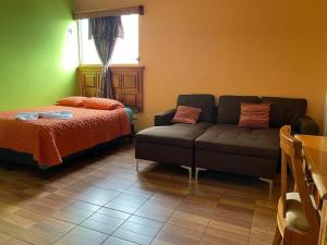 a living room with a couch and a bed at Hotel del Carmen in Retalhuleu