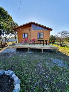 une cabine avec deux chaises roses sur une terrasse en bois dans l'établissement Cabañas Llepu, à Linares