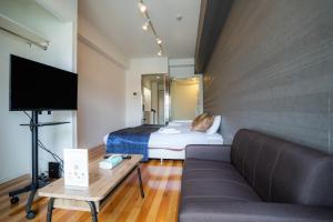 a hotel room with a bed and a couch at S-Presso Namba Parks Street in Osaka