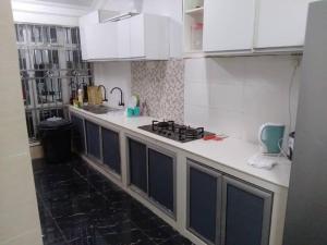 uma cozinha com armários brancos e um fogão em Homestay Legacy Yumai Kuala Rompin em Kuala Rompin