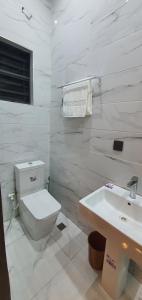 a white bathroom with a toilet and a sink at Sapphire Residences by Crystal in Ikeja