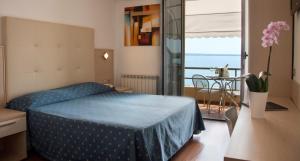 a bedroom with a bed and a table and a balcony at Hotel Ca' Serena in Sirmione