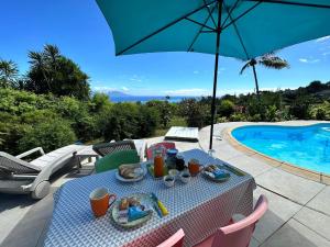 a table with a tray of food and an umbrella next to a pool at Kahea Ragni in Punaauia
