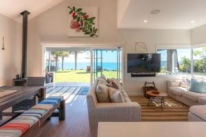 a living room with a couch and a tv at The Point - Stay Waiheke in Onetangi
