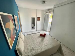 Apartamento Auge da Bahia في سلفادور: غرفة نوم بسرير عليه غرض احمر