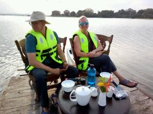 two people sitting on a dock near the water at Priyanna Guest, Forest view in Polonnaruwa