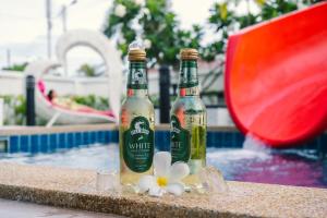 two bottles of beer sitting next to a swimming pool at so happy pool villa hua hin in Ban Bo Fai