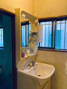 a bathroom with a sink and a mirror and windows at 大泉学園ヴィラーアニメーションの起源地にある日本の日常が体験できるまるまる貸切一軒家 in Katayama