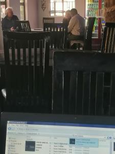 um ecrã de computador com pessoas sentadas em cadeiras num restaurante em Okahatjipara Lodge 