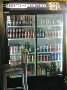 um frigorífico cheio de bebidas e uma cadeira em Okahatjipara Lodge 
