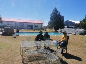 un grupo de personas sentadas alrededor de una mesa cerca de una piscina en Okahatjipara Lodge, 