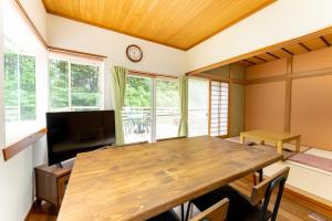 una sala da pranzo con tavolo in legno e TV di Green Oasis Cottage Hakone Sengokuhara - グリーンオアシスコテージ箱根仙石原 a Sengokuhara