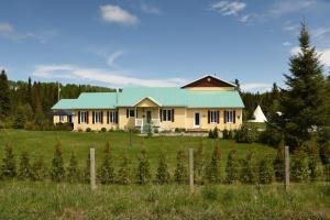 une maison avec un toit vert dans un champ dans l'établissement Gîte de la Montagne Enchantée, à Métabetchouan