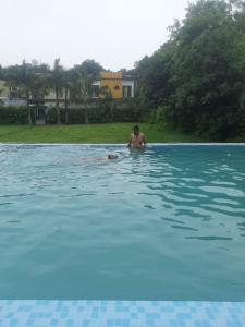 Ein Mann im Wasser im Schwimmbad. in der Unterkunft The HeartWood Farms Inn in Rāmnagar