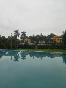 uitzicht op een zwembad met palmbomen en huizen bij The HeartWood Farms Inn in Rāmnagar
