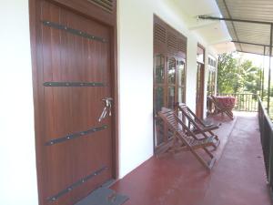 ein Paar Schaukelstühle auf der Veranda eines Hauses in der Unterkunft Chamodya Home Stay in Ella