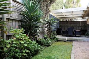 eine Terrasse mit Stühlen und einer Palme neben einem Zaun in der Unterkunft Sunderland Escape in Sunset Strip