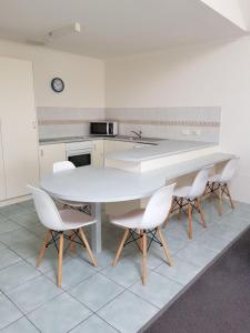 Bayview Apartments في ميريمبولا: مطبخ مع طاولة بيضاء وكراسي