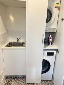 eine kleine Küche mit Spüle und Waschmaschine in der Unterkunft Sydney CBD stylish water view apartment 58 in Sydney