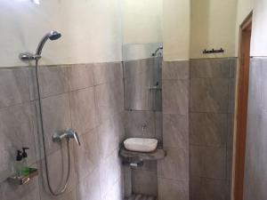 uma casa de banho com um chuveiro, um lavatório e um WC. em Kenari Diwang em Ubud
