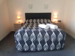 a black and white bed in a room with two lamps at Bayview Apartments in Merimbula +16 photos
