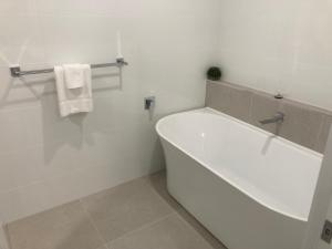 a white bathroom with a tub and a towel at Kincaid@230 in Wagga Wagga +3 photos