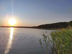 una puesta de sol sobre un lago con la puesta de sol en Kaszuby dom nad jeziorem Szczytno Duże, en Dobrzyń