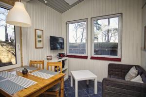 a living room with a table and chairs and windows at Dünenchalet Nr 49 in Göhren