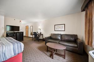 a hotel room with a couch and a bed and a table at AmericInn by Wyndham Ames in Ames
