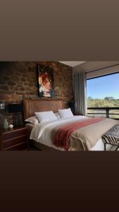 1 dormitorio con 1 cama grande y pared de ladrillo en LEOPARD'S VIEW MOUNTAIN VILLA @ Steinheim Game Farm & Camping, en Prospect