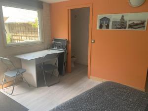 een oranje kamer met een bureau en een raam bij logements vue sur mer ,chambre et cuisine équipée ,accès indépendant, terrasse in Trélévern