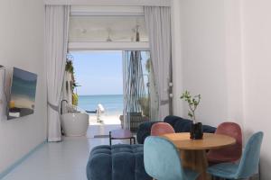 Adika - The beachfront Loft في تشالوكلوم: غرفة معيشة مع طاولة وكراسي والمحيط
