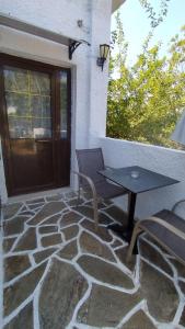 a patio with a table and a bench next to a door at Perix House in Neos Marmaras