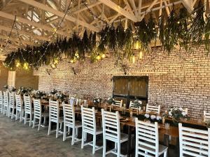 una mesa larga con sillas blancas y una pared de ladrillo en Tula Baba Game Lodge, en Brits
