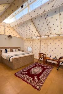 a bedroom with a bed and a rug in a room at Jaisal heritage desert camp in Jaisalmer