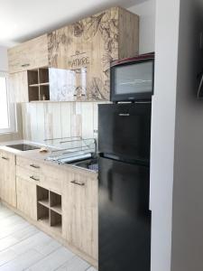 a kitchen with a black refrigerator and wooden cabinets at CaSa Stai in Mangalia