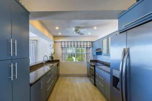 eine blaue Küche mit Küchengeräten aus Edelstahl und blauen Schränken in der Unterkunft Westshore Beach House by Blue Sky Luxury in Saint James