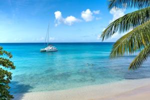 ein Boot im Ozean mit zwei Menschen im Wasser in der Unterkunft Westshore Beach House by Blue Sky Luxury in Saint James