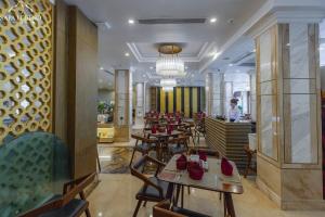 Sapa Legend Hotel & Spa في سابا: مطعم بطاولات وكراسي وشخص في الخلفية