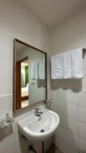 a white bathroom with a sink and a mirror at Lubdhaka Canggu in Canggu