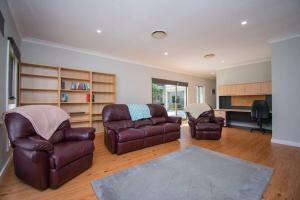 Paperbark Retreat في ألباني: غرفة معيشة مع أريكة جلدية وكراسي
